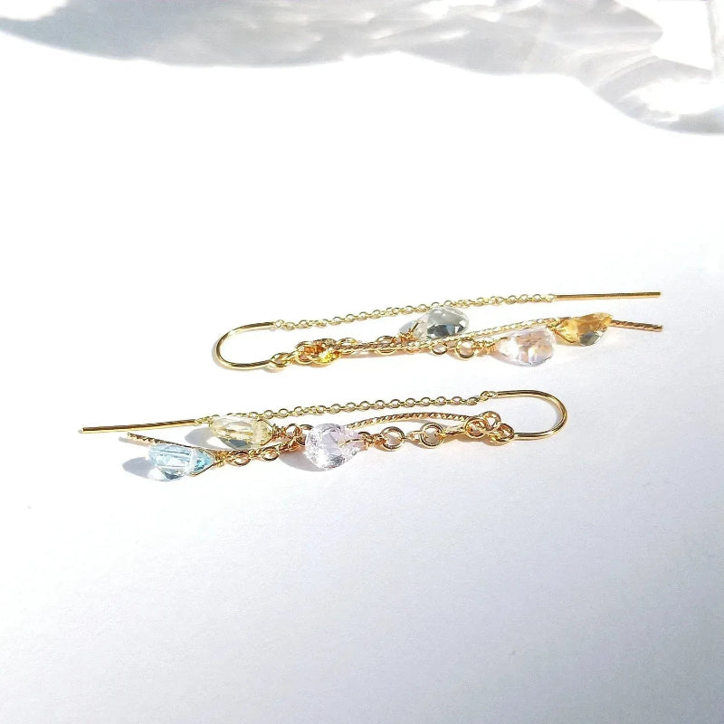 Gold earrings with colorful beads on a white background