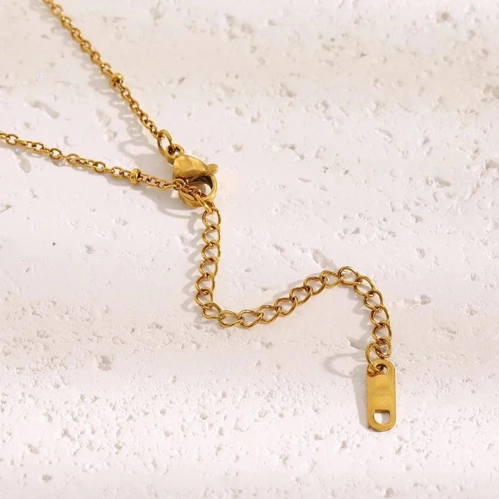 Gold chain necklace on a textured white surface