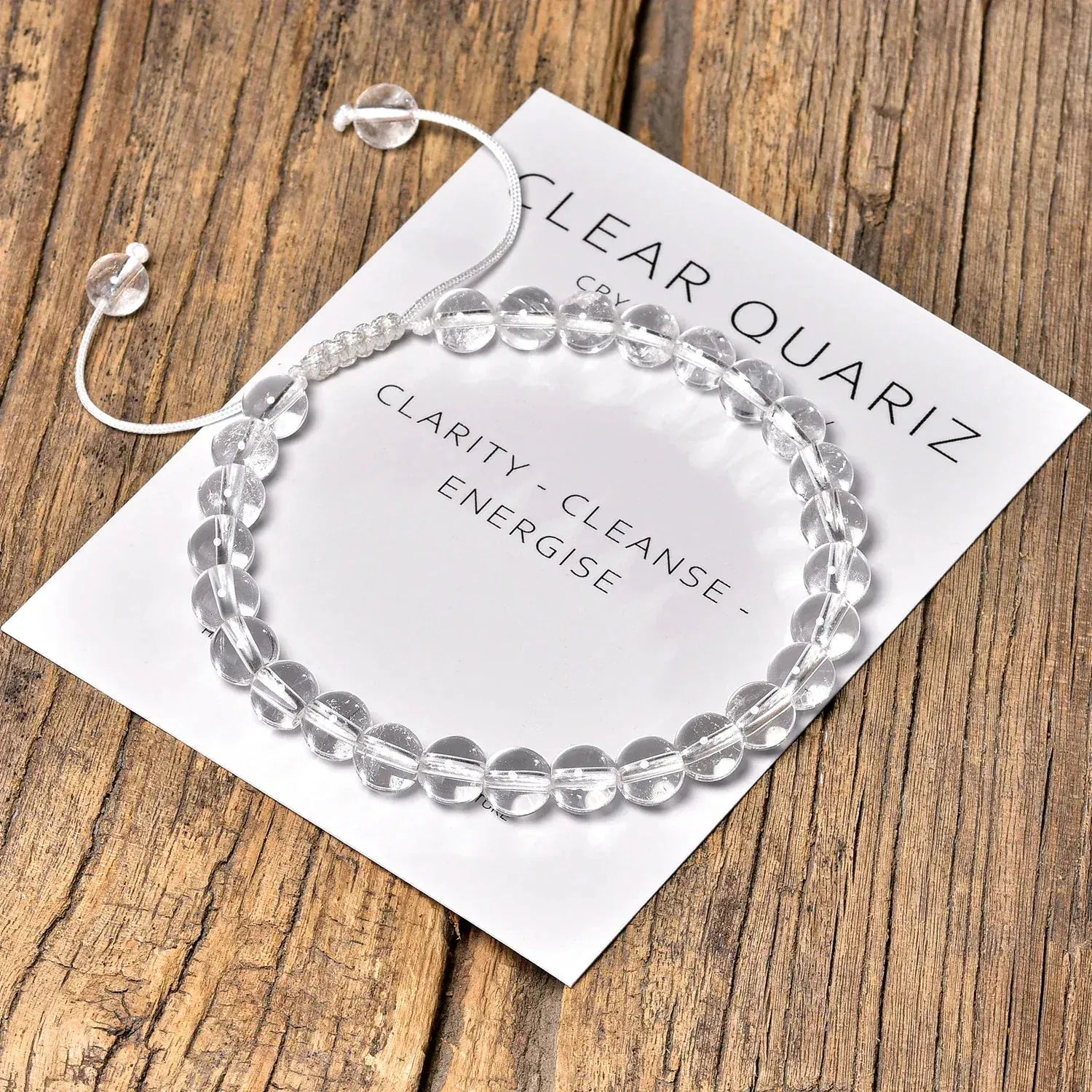 Clear quartz bracelet on a card with text on a wooden surface