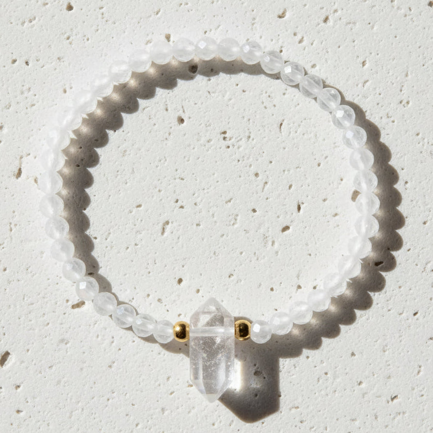 White beaded bracelet with a clear crystal pendant on a white background