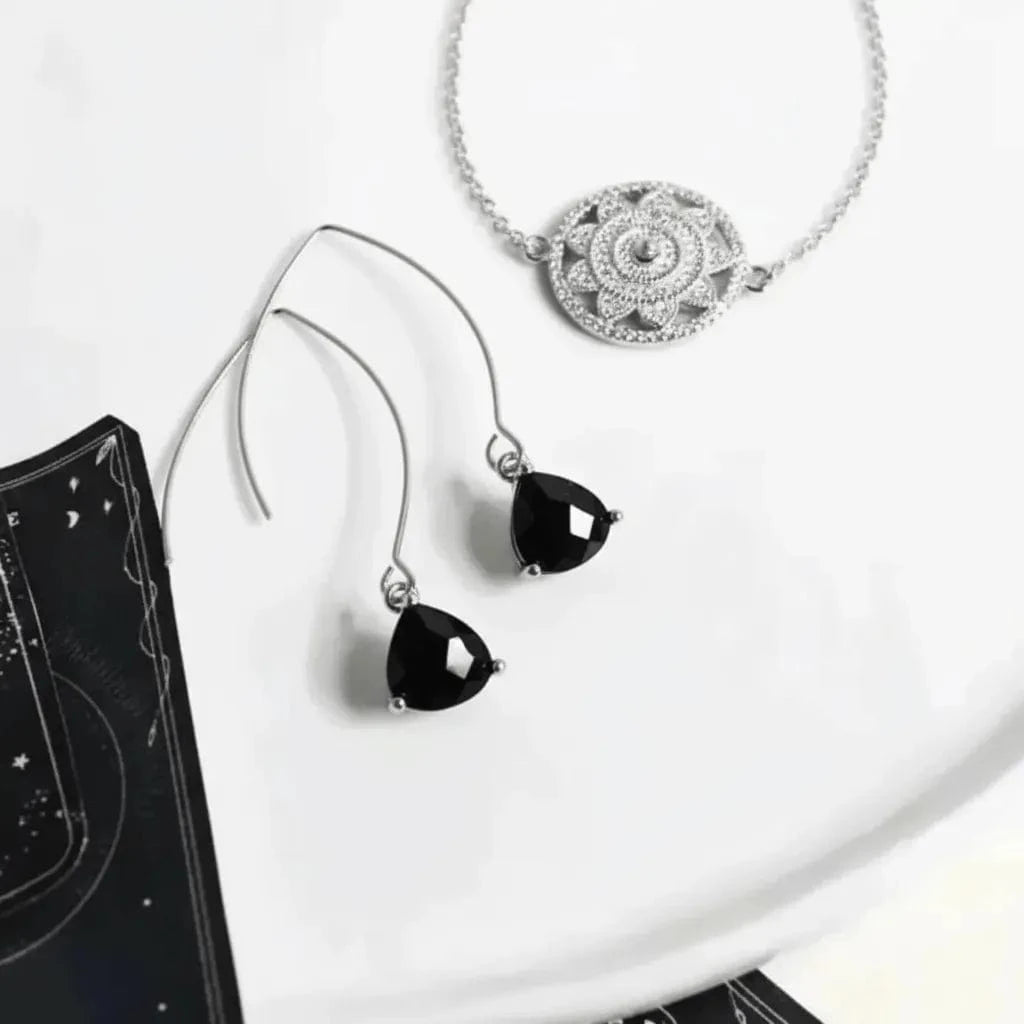 Silver jewelry set with black gemstones on a white surface
