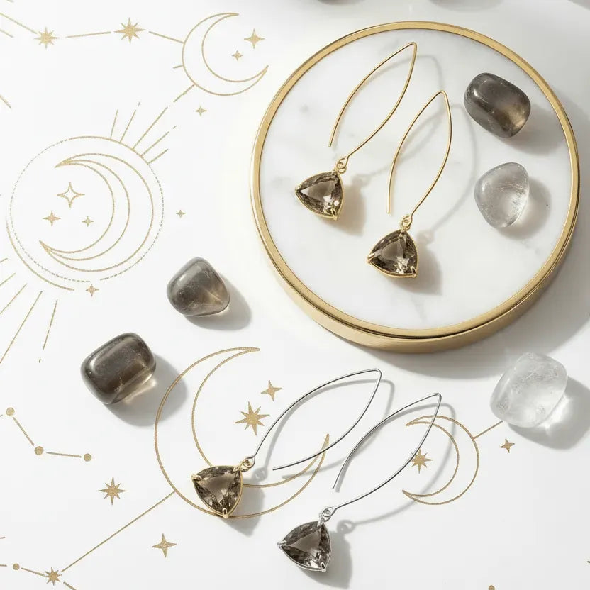 Gold earrings with heart-shaped gemstones on a white surface with celestial designs.