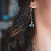 Close-up of a person wearing a dangling earring with a gemstone.