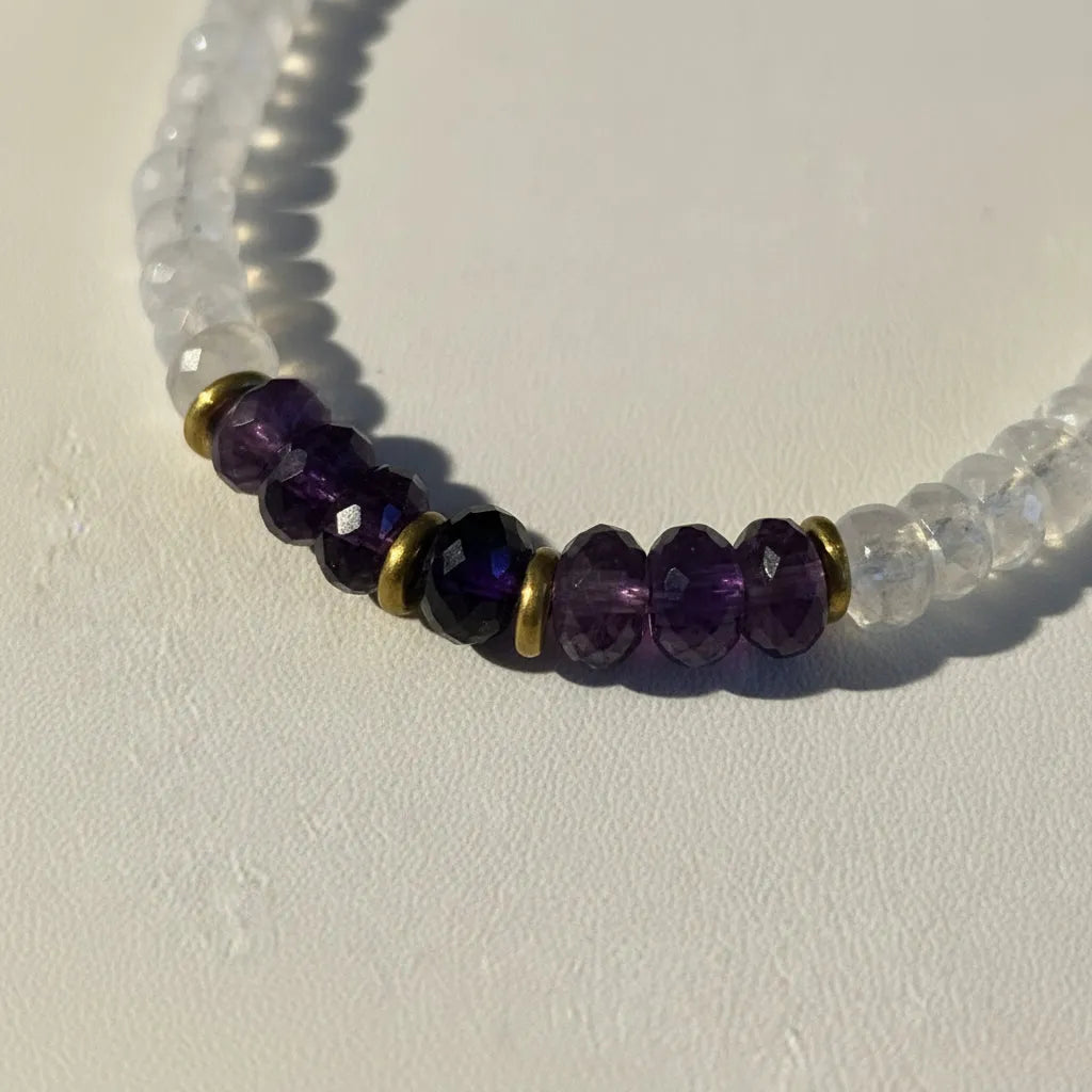 Close-up of faceted amethyst and graduated moonstone beads on a hand-strung necklace