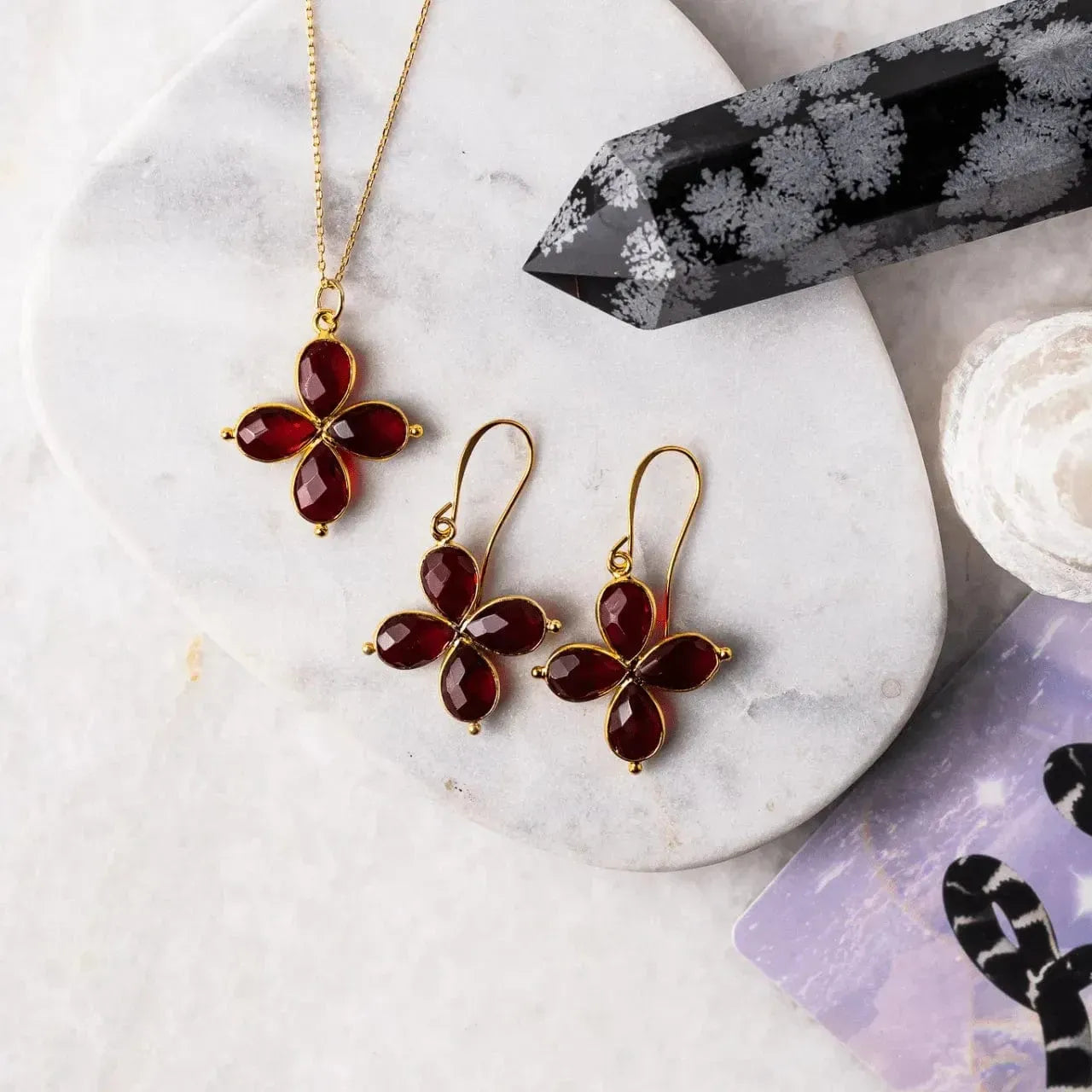 clover shaped jewelry set with red stones on a marble surface