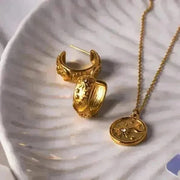 Gold hoop earrings and necklace on a textured white surface
