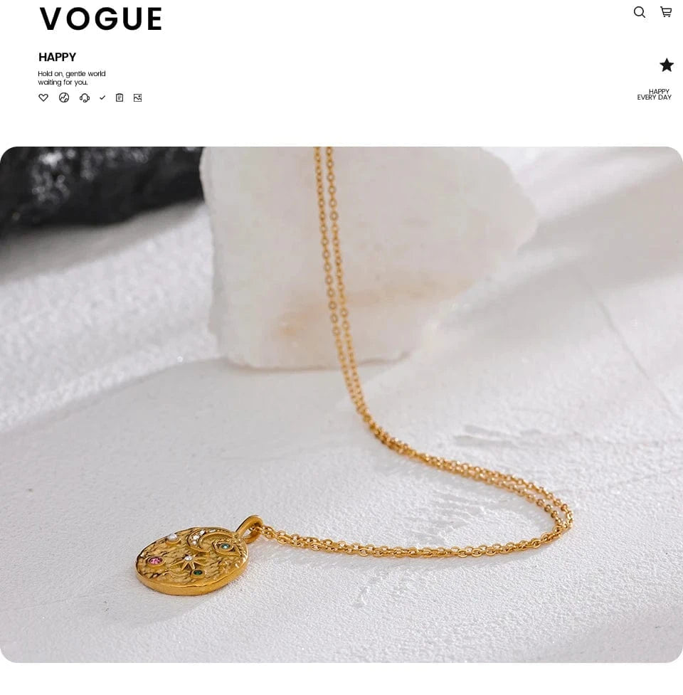 Gold necklace with a pendant on a white surface, displayed on a Vogue website.