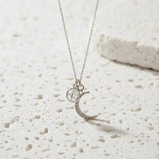Necklace with a crescent moon and gemstone pendant on a white background