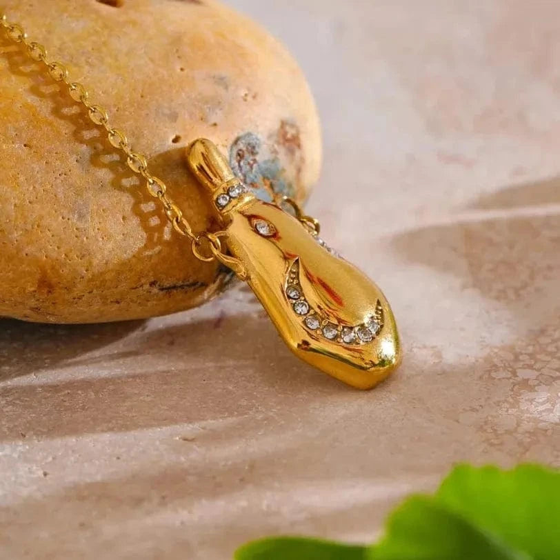 Gold necklace with a pendant on a stone surface