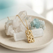 Gold necklace with a pendant on a plate with crystals