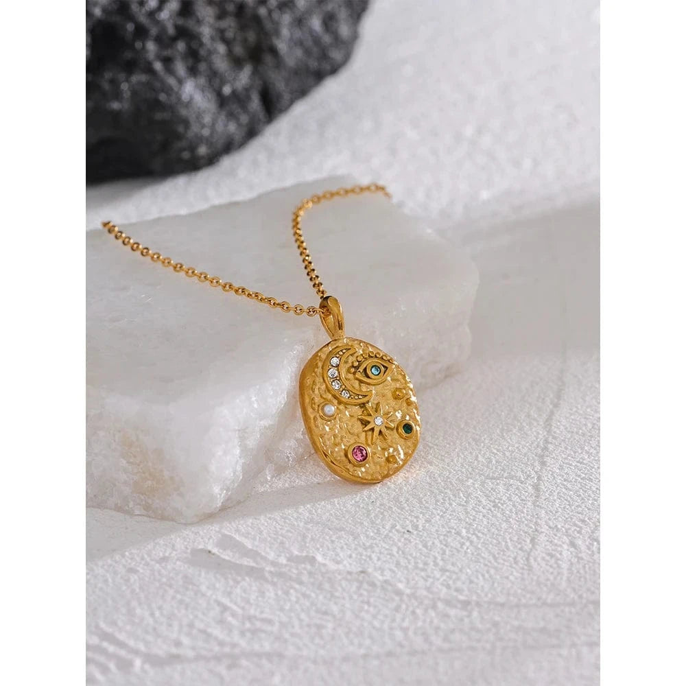 Gold necklace with a decorative pendant on a textured white surface