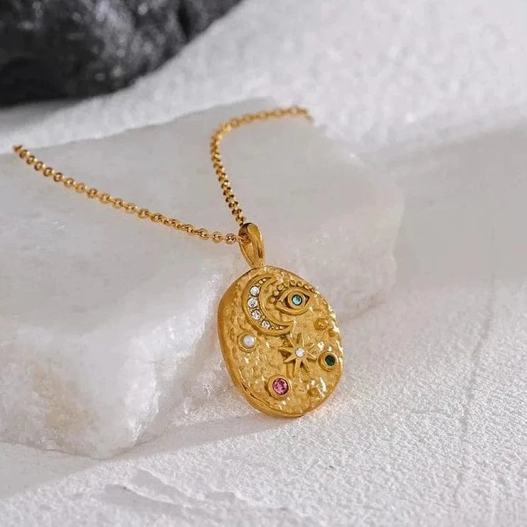 Gold necklace with a decorative pendant on a textured white surface