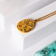 Gold necklace with a decorative pendant on a white surface