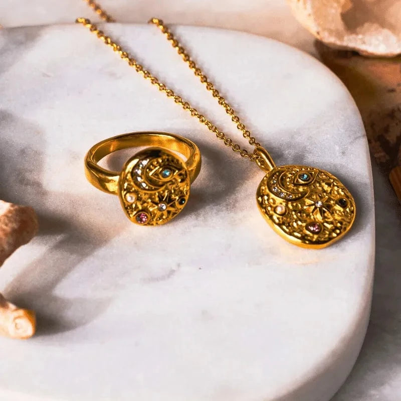Gold ring and necklace with gemstones on a marble surface