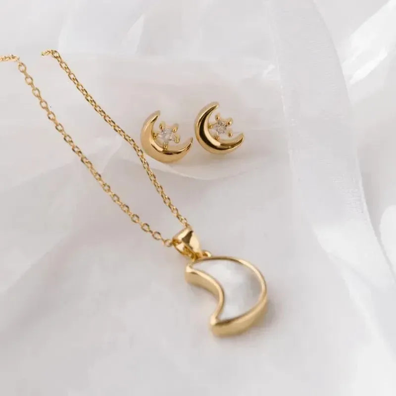 Gold necklace and earrings with moon design on a white background