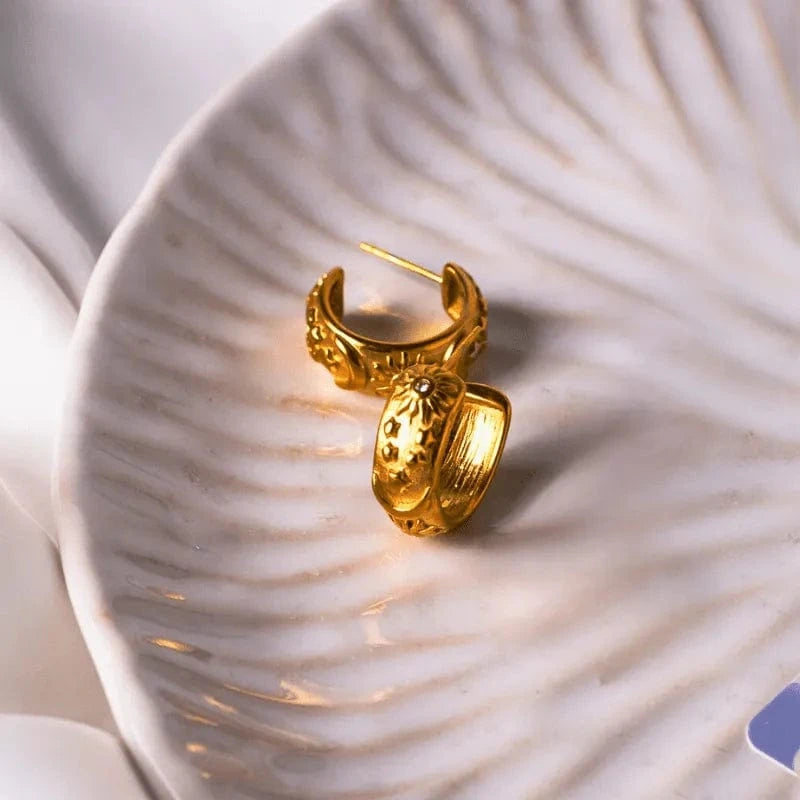 Gold hoop earrings on a textured white surface