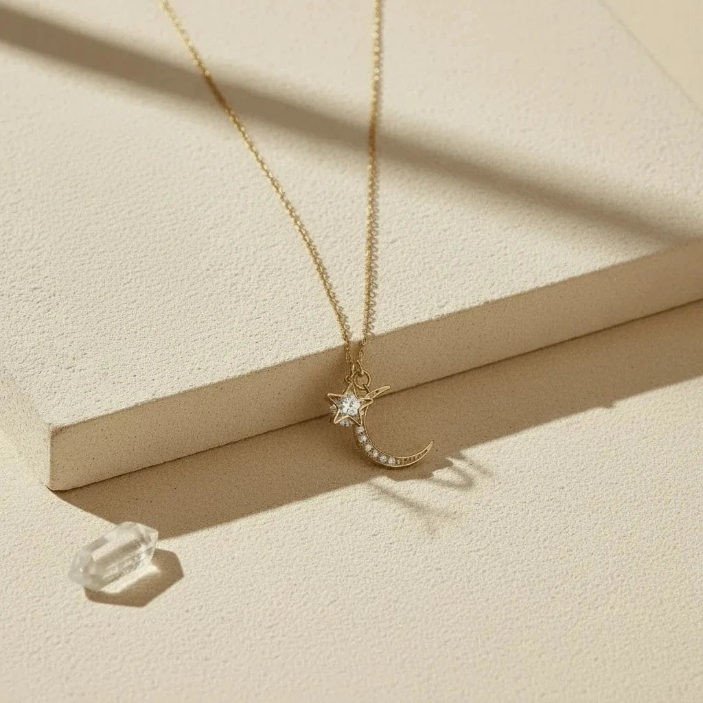 Gold necklace with a moon and star pendant on a beige surface