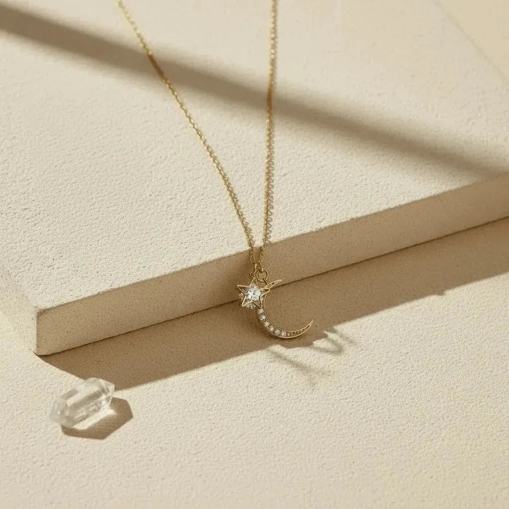 Gold necklace with a moon and star pendant on a beige surface