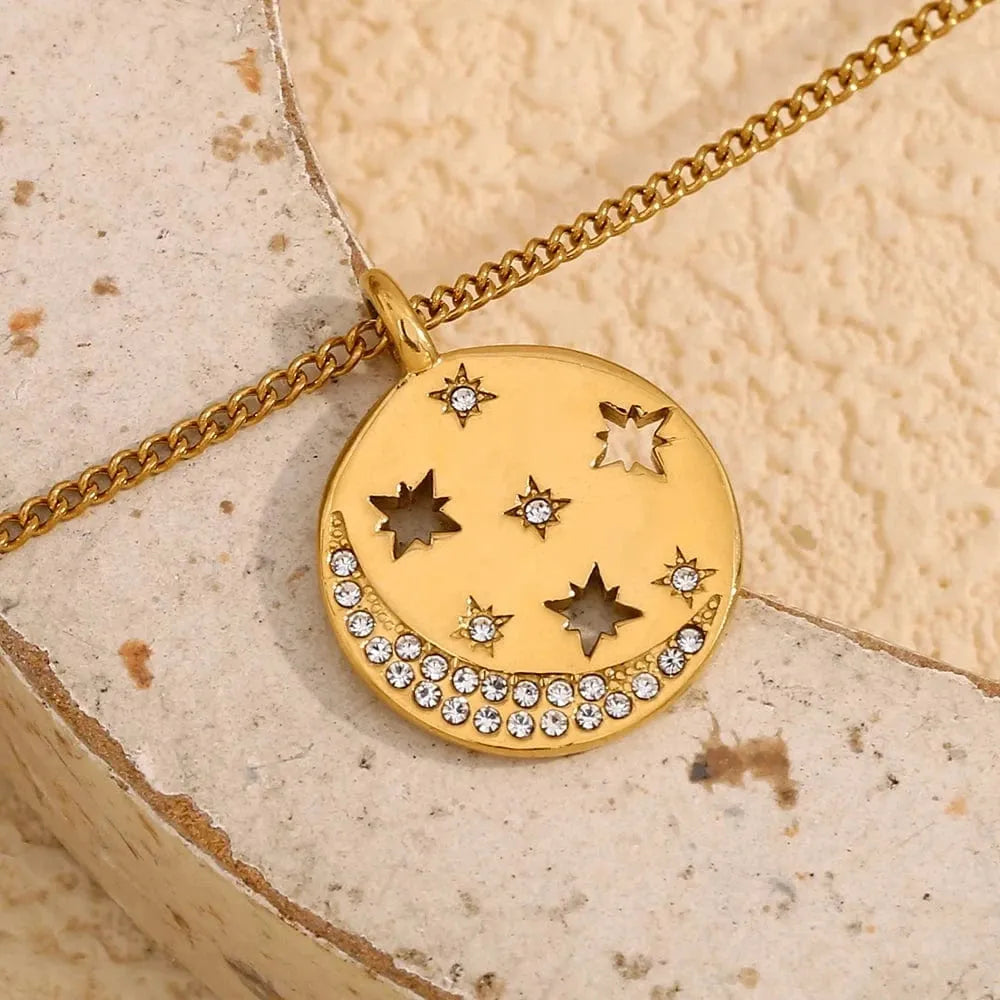 Gold necklace with star-shaped pendant on a textured beige surface