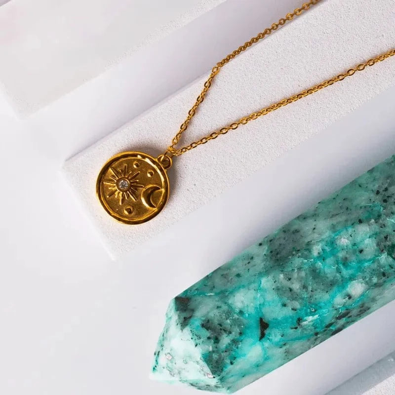 Necklace with a gold pendant featuring a pink gemstone and pearl-like elements on a white background