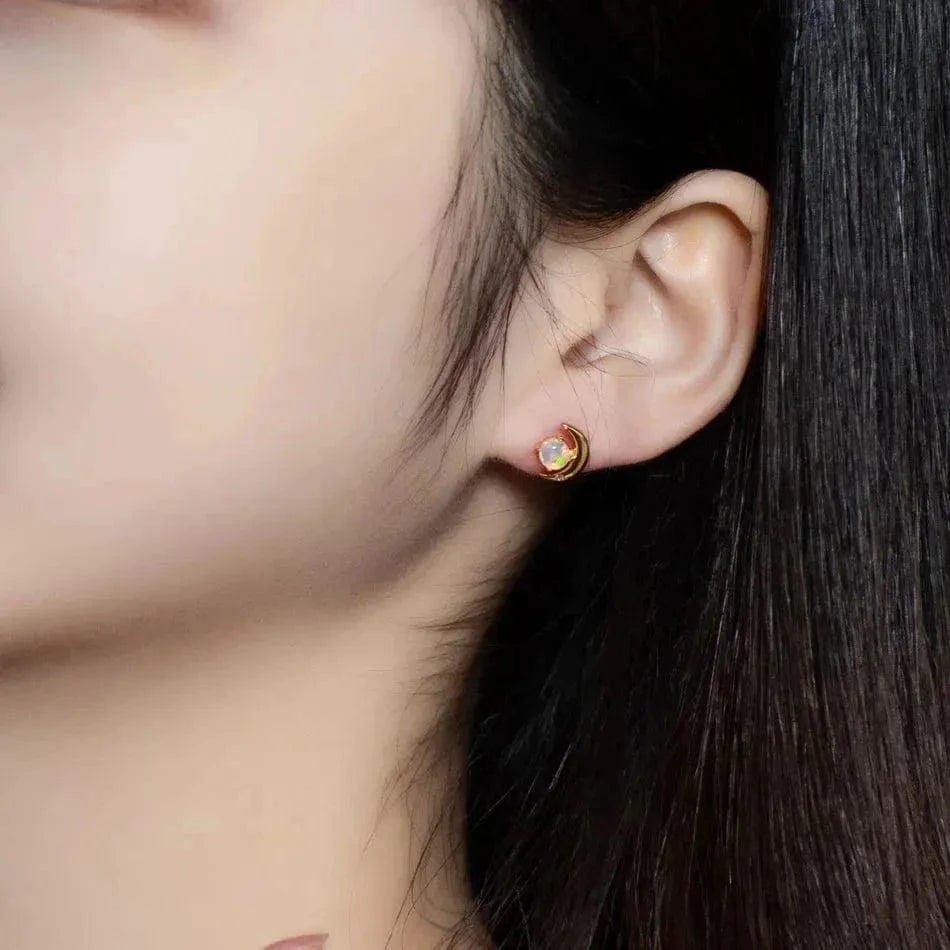 Close-up of an ear wearing a gold earring with a gemstone.