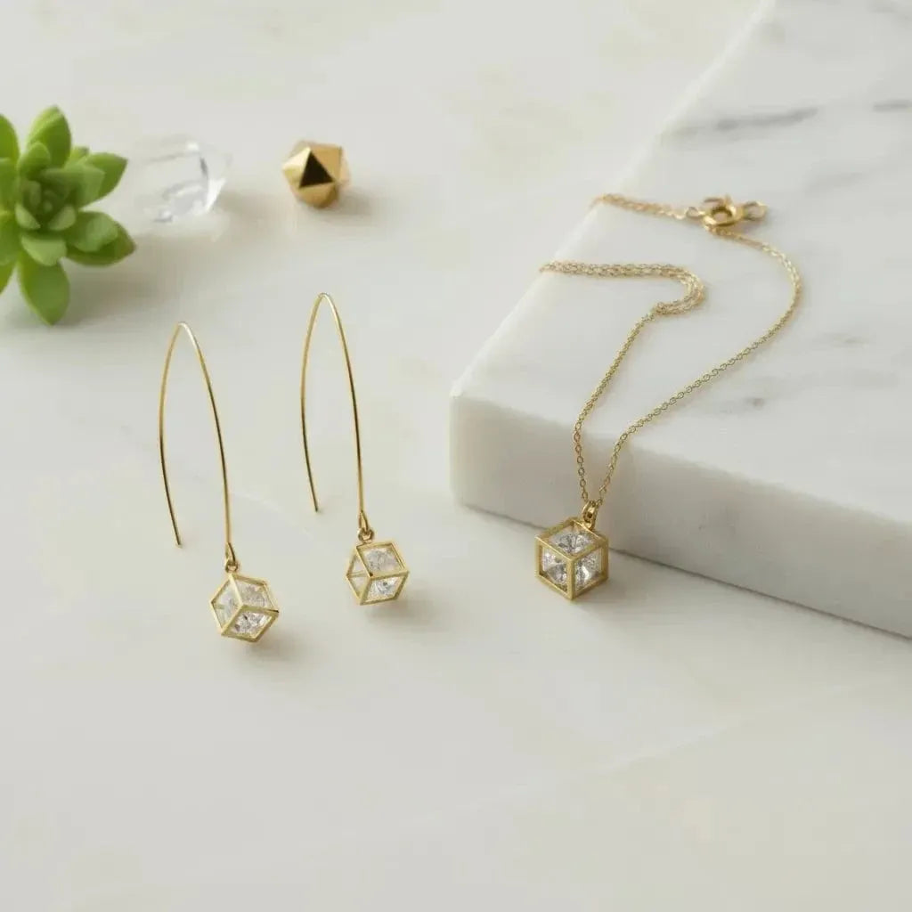 Gold cube-shaped earrings and necklace on a white background