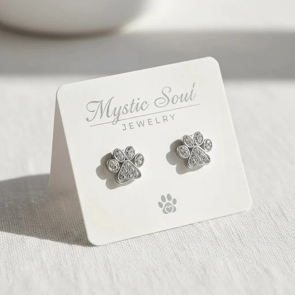 Silver paw print earrings on a 'Mystic Soul Jewelry' card.