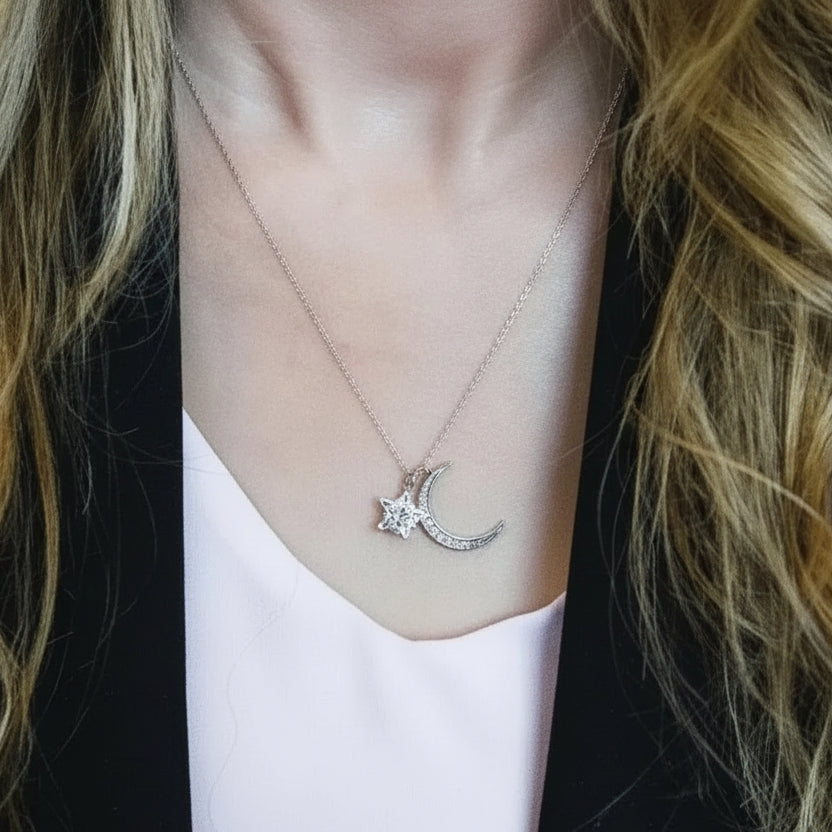 Necklace with pink gemstones and a moon and star pendant on a person wearing a white top.