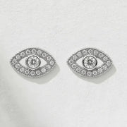 Pair of silver eye-shaped earrings with clear gemstones on a light gray background