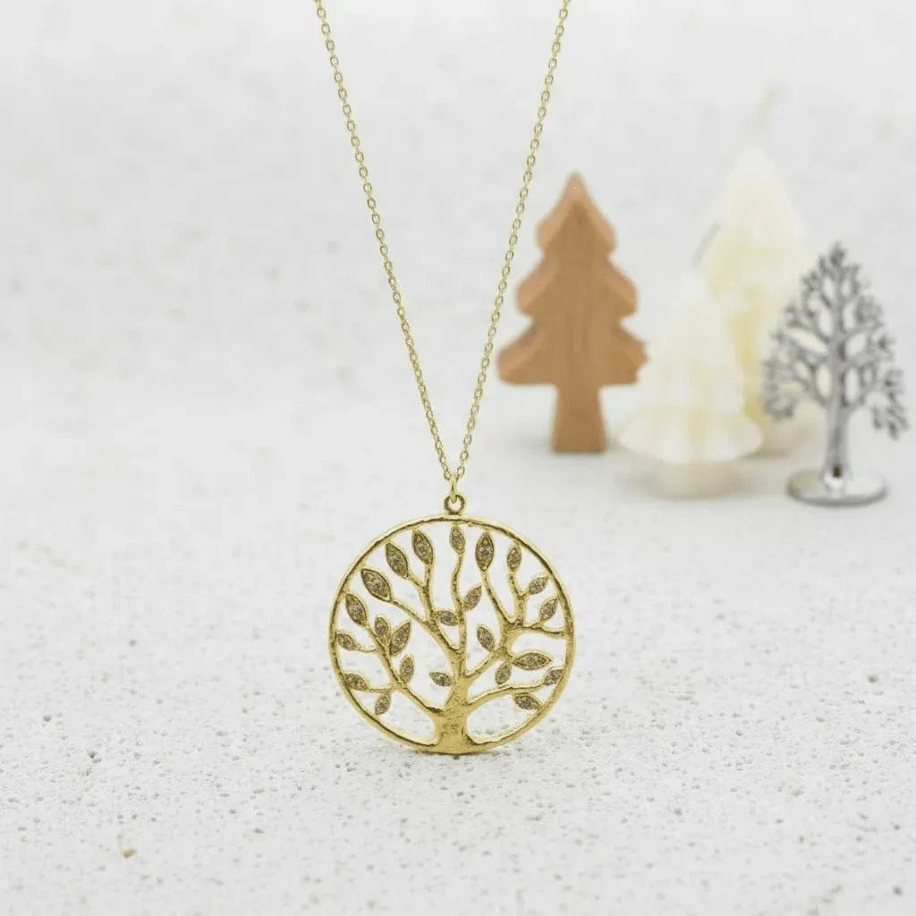 Gold tree-shaped pendant necklace on a light background