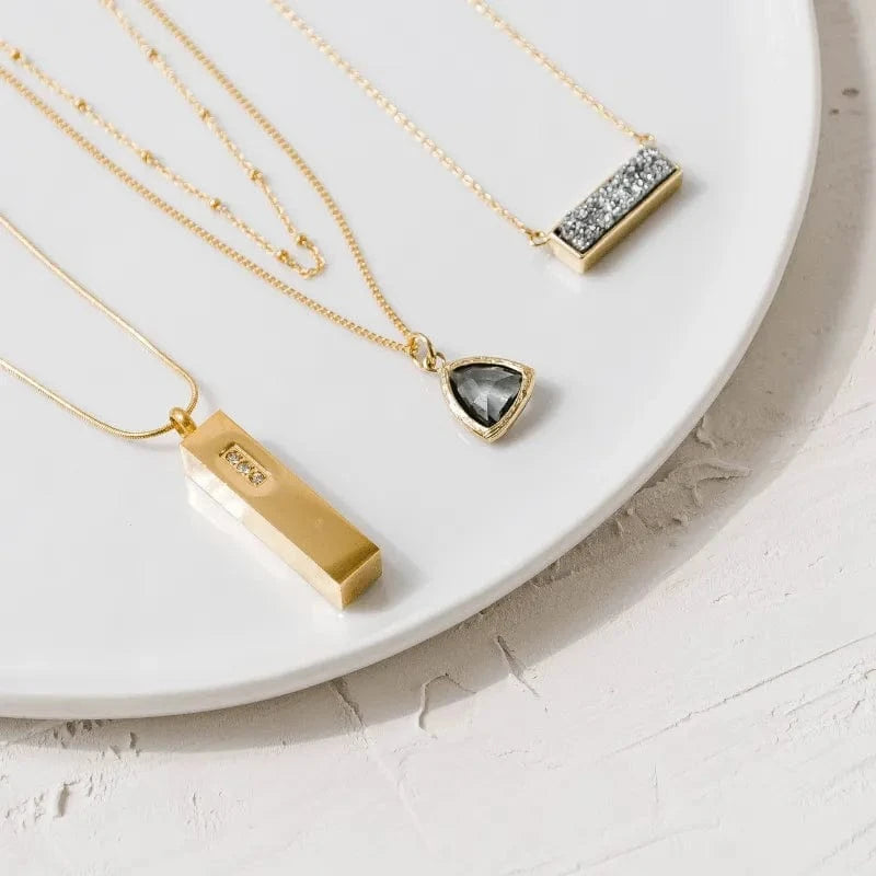 Gold necklaces with various pendants on a white surface