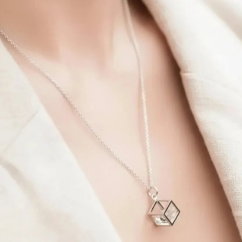 Silver necklace with a geometric pendant worn by a person