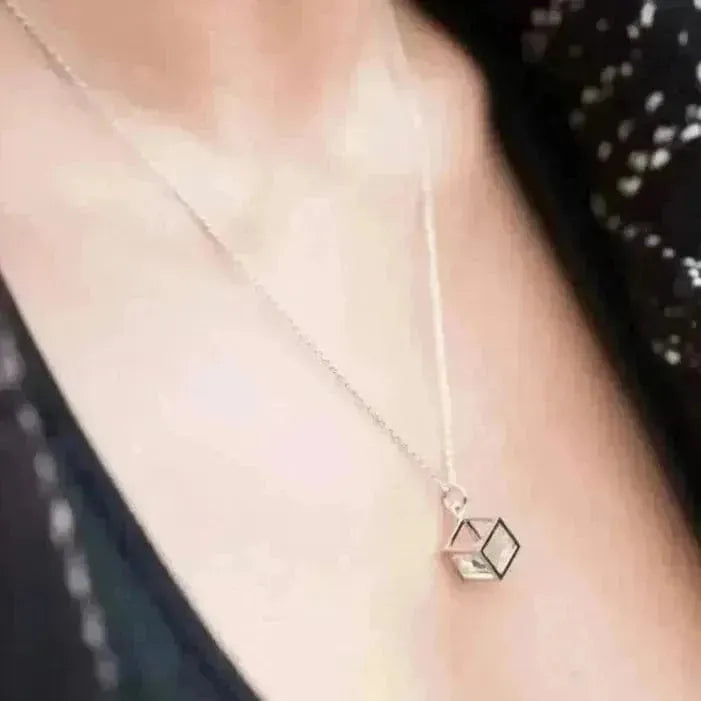 Silver necklace with a geometric pendant worn by a person