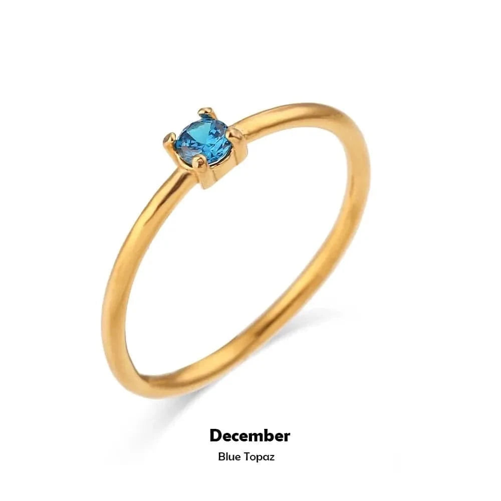 Gold ring with a blue gemstone on a white background, labeled 'December Blue Topaz'.