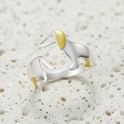 Silver dog-shaped ring with gold accents on a gray background