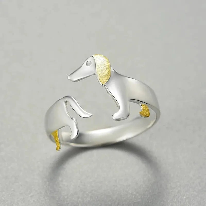 Silver dog-shaped ring with gold accents on a gray background