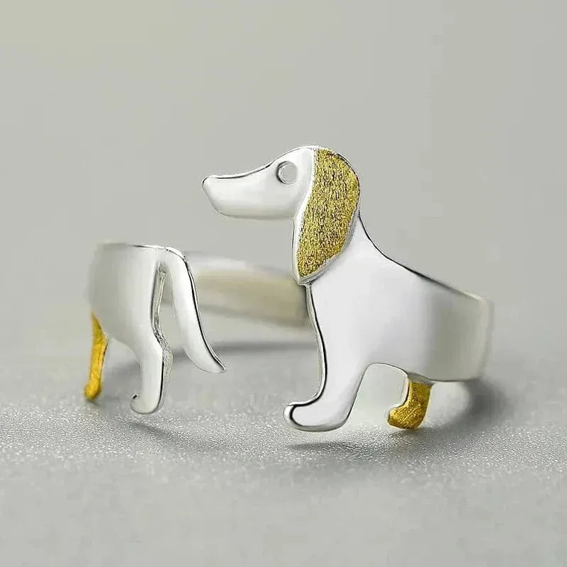 Silver dog-shaped ring with gold accents on a gray background
