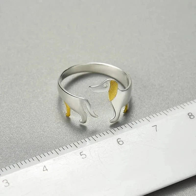 Silver ring with gold accents on a gray surface with a ruler for scale.