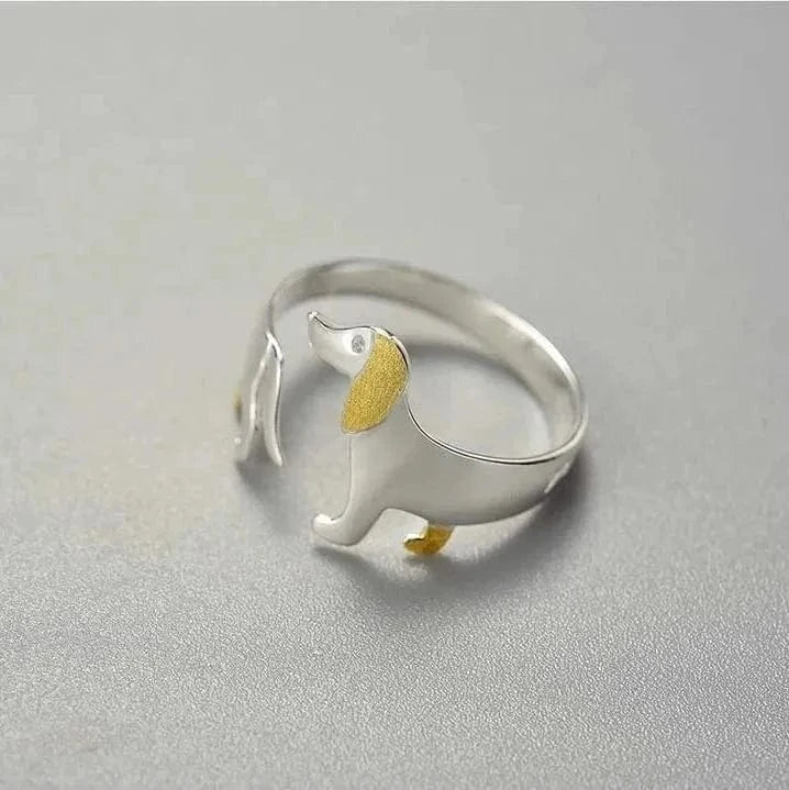 Silver ring with a small dog design on a gray background