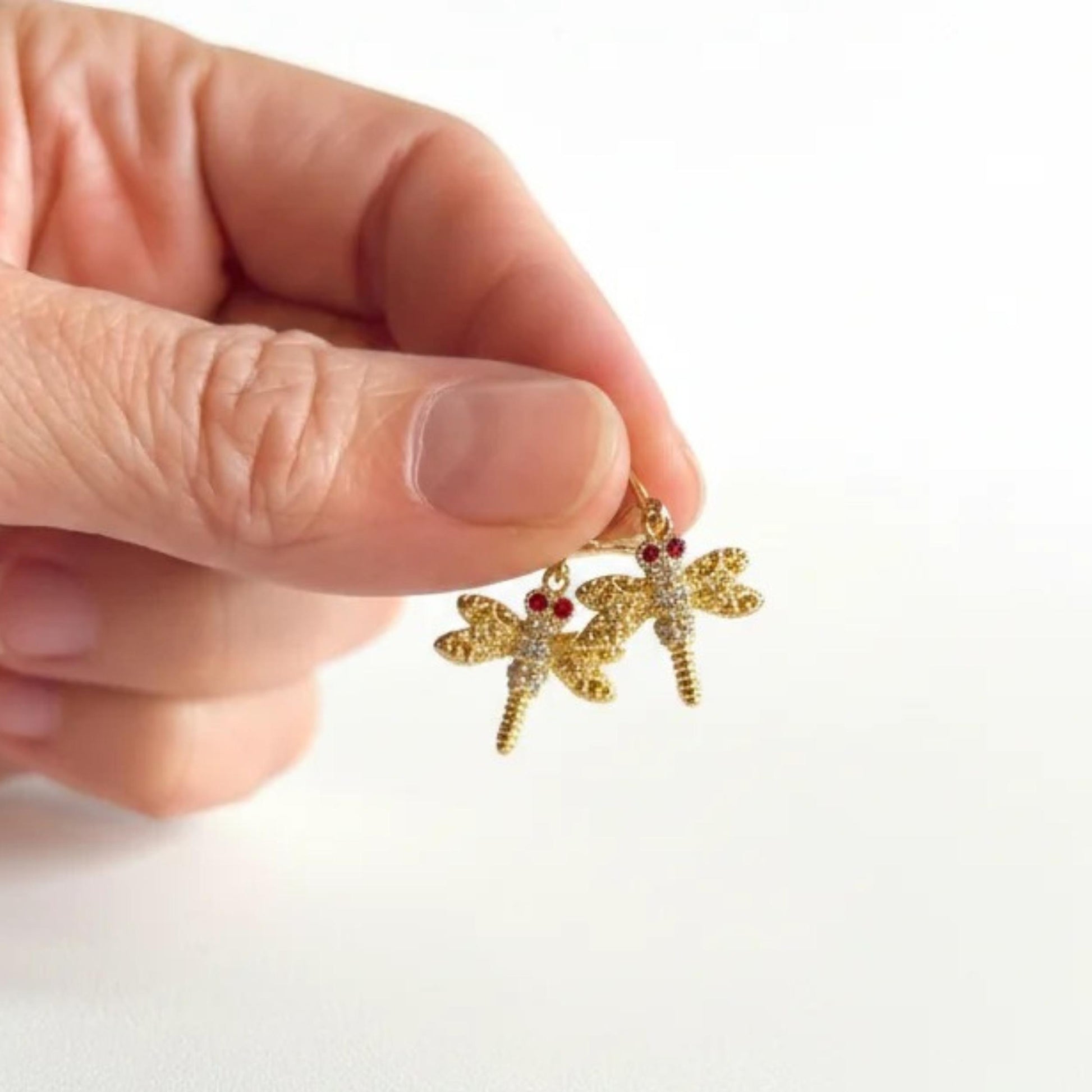 Gold crystal dragonfly leverback earrings held in hand for scale — spirit animal jewelry