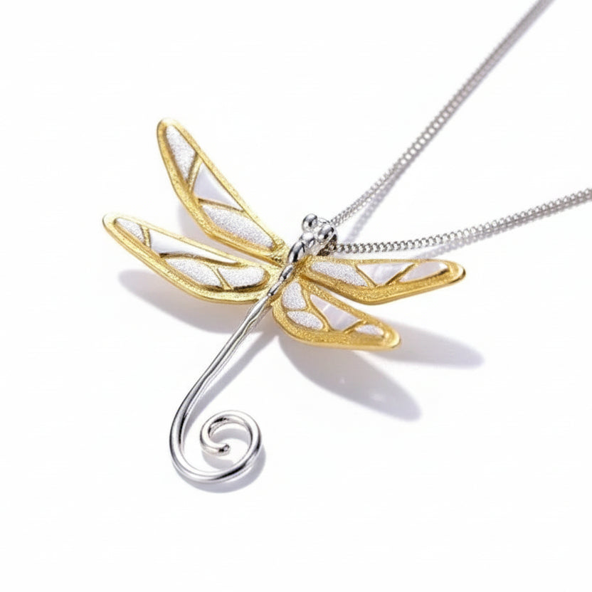 Dragonfly-shaped pendant on a chain against a natural background