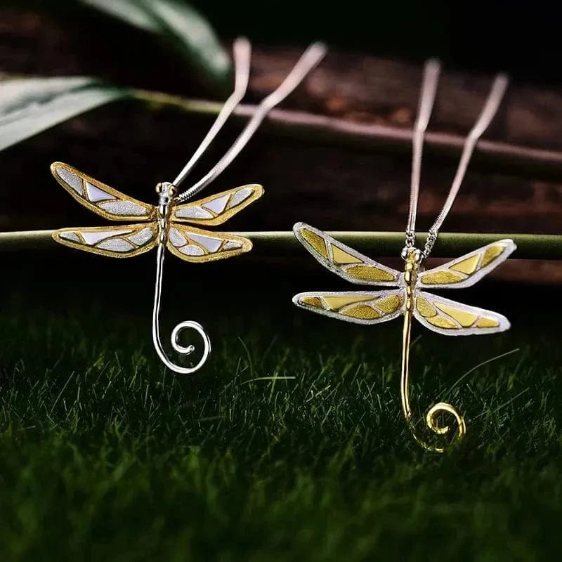 Two dragonfly-shaped pendants on a grassy background