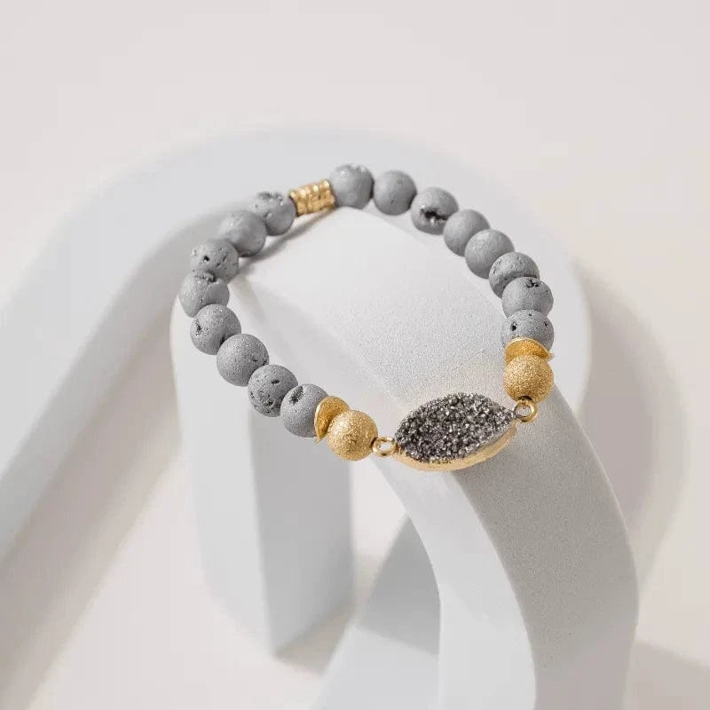 Bracelet with gray beads and gold accents on a white stand