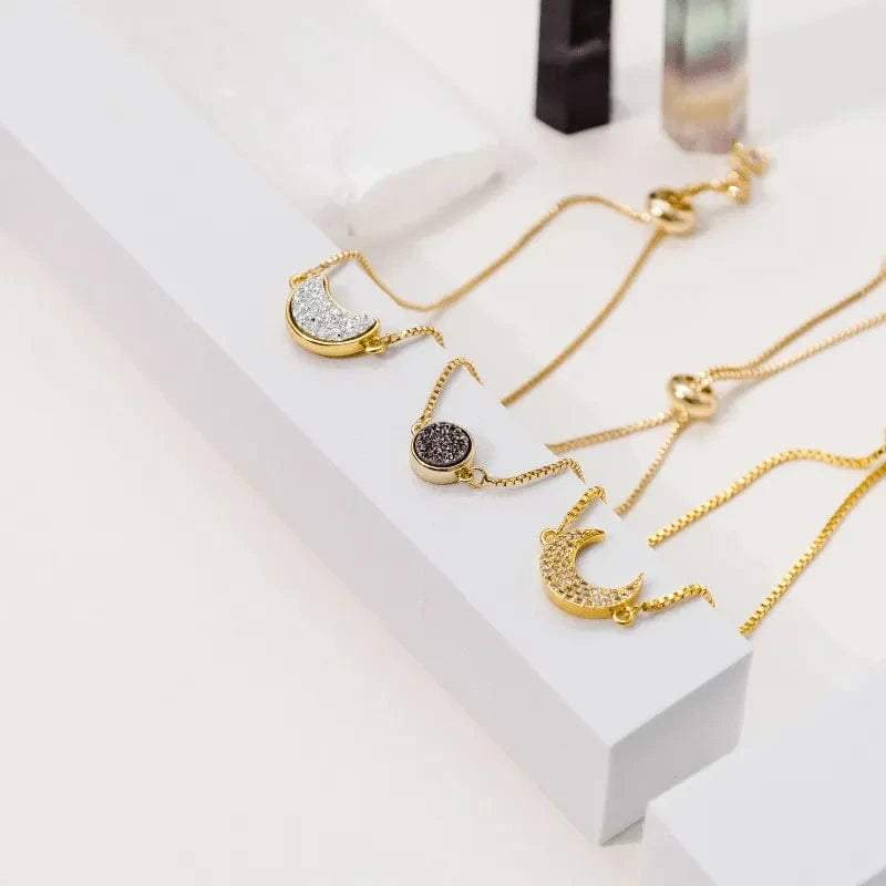 Gold necklaces with moon designs on a white surface