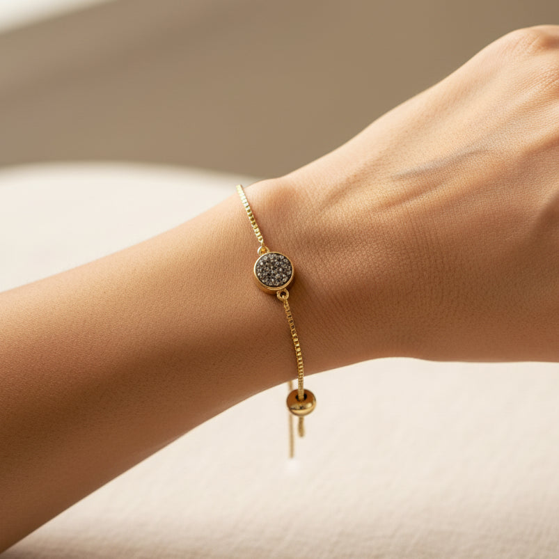 Gold bracelet with a gemstone on a white surface with crystal-like objects.