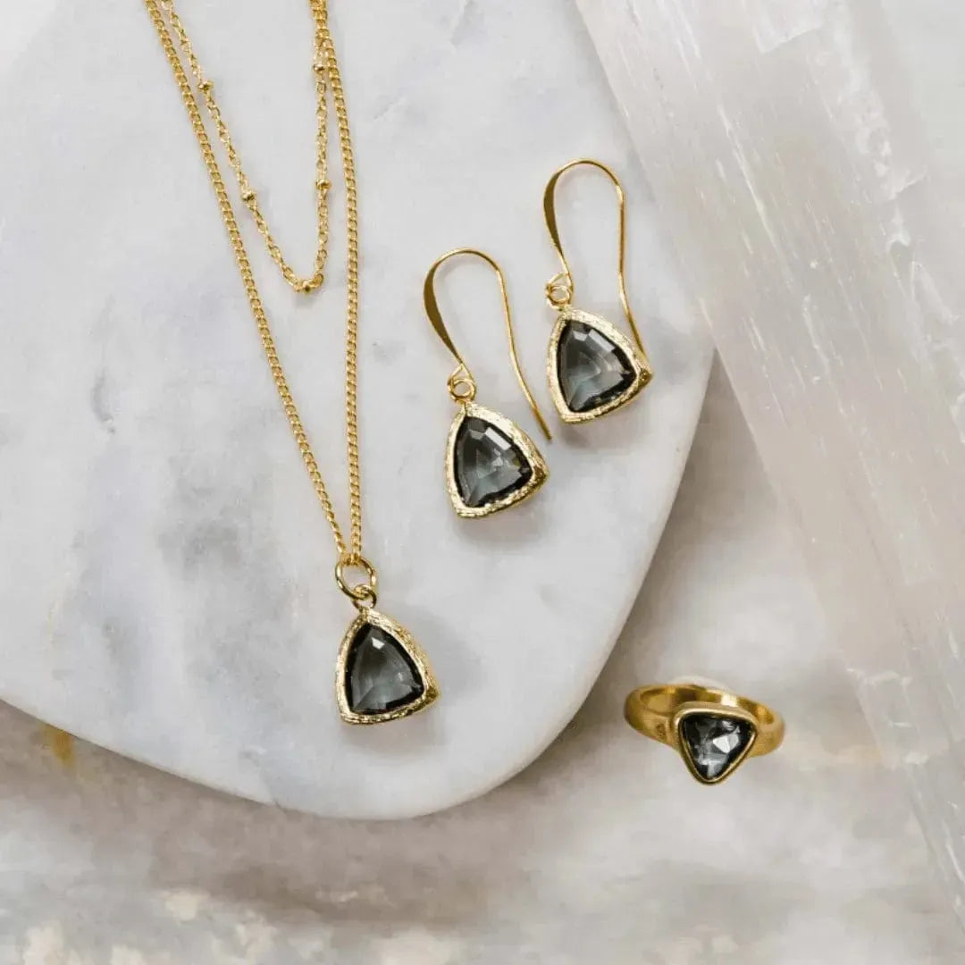 Gold jewelry set with gemstones on a marble surface