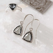 Silver teardrop earrings with black gemstones on a white surface