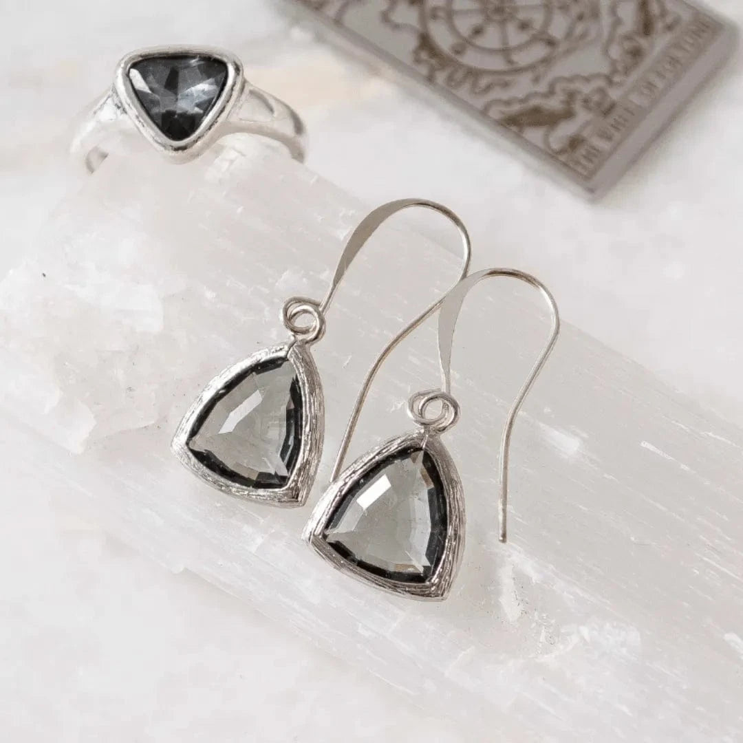 Silver teardrop earrings with black gemstones on a white surface