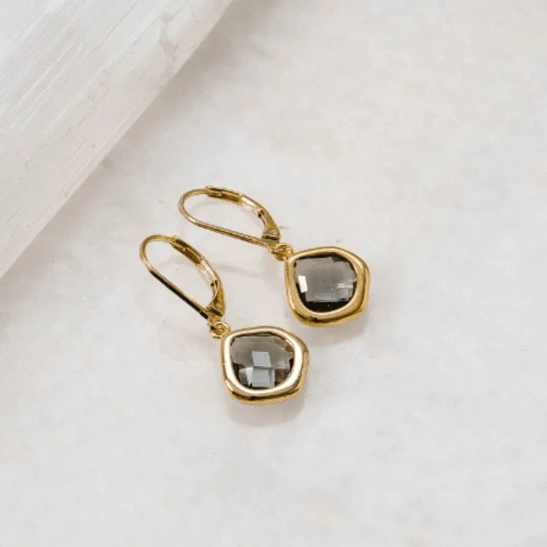 Gold earrings with smoky quartz stones on a light background