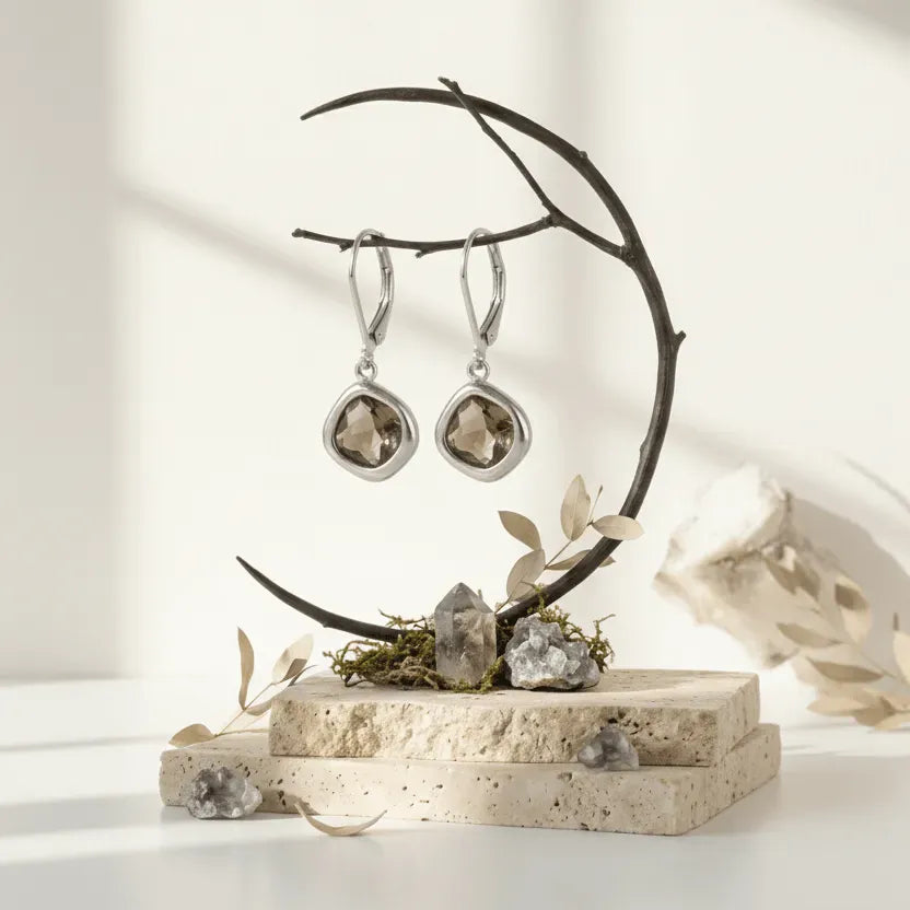 Silver earrings on a decorative stand with stones and leaves